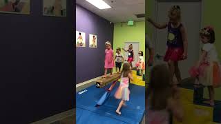 Kids walk across gymnastics balance beam then boy jumps off backwards and hits chin