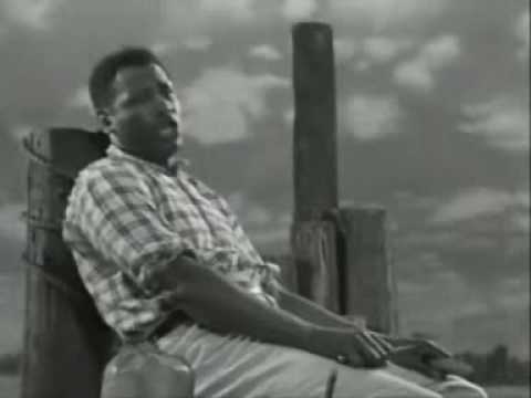 From Showboat's 2nd version (1936) Paul Robeson - Ol' Man River Ol' Man River (Jerome Kern - Oscar Hammerstein II) Lyrics from the Original Libretto Dare's an ol' man cal'd de Mississipi Dat's de ol' man dat I'd lek to be Whot does he care iv de world gets trauble Whot does he care iv de land lev's free. Ol' man river, Dat ol' man river He mus'know sumpin' But don't say nuthin', He jes'keeps rollin' He keeps on rollin' along. He don' plant taters, He don't plant cotton, An' dem dat plants'em is soon forgotten, But ol'man river, He jes keeps rollin'along. You an'me, we sweat an' strain, Body all achin' an' racket wid pain, Tote dat barge! Lif' dat bale! You gits a little drunk An' you lands in jail. Ah gits weary An' sick of tryin' Ah'm tired of livin' An' skeered of dyin', But ol' man river, He jes'keeps rolling' along. [Colored folks work on de Mississippi, Colored folks work while de white folks play, Pullin' dose boats from de dawn to sunset, Gittin' no rest till de judgement day. Don't look up An' don't look down, You don' dast make De white boss frown. Bend your knees An'bow your head, An' pull date rope Until you' dead.) Let me go 'way from the Mississippi, Let me go 'way from de white man boss; Show me dat stream called de river Jordan, Dat's de ol' stream dat I long to cross. O' man river, Dat ol' man river, He mus'know sumpin' But don't say nuthin' He jes' keeps rollin' He keeps on rollin' along. (Long ol' river forever keeps rollin' on...) He don' plant tater <b>...</b>