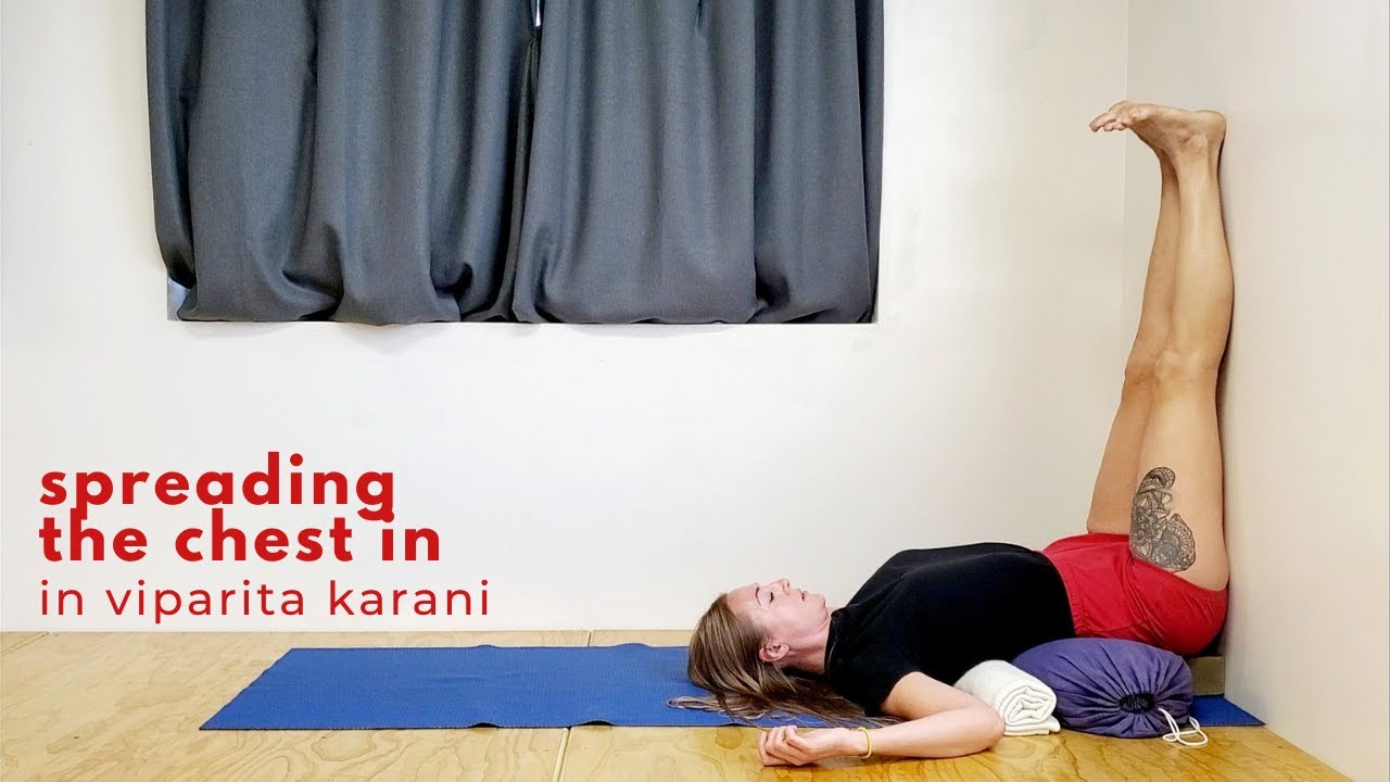 Young sporty woman practising yoga on mat near grunge beige wall studio  background, girl performs legs up half candle or Viparita Karani pose  exercise, side view, mental physical health care concept Stock