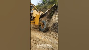 Land grading: caterpillar 12h motor grader shaping hillside for road construction
