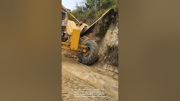 Land grading: caterpillar 12h motor grader shaping hillside for road construction