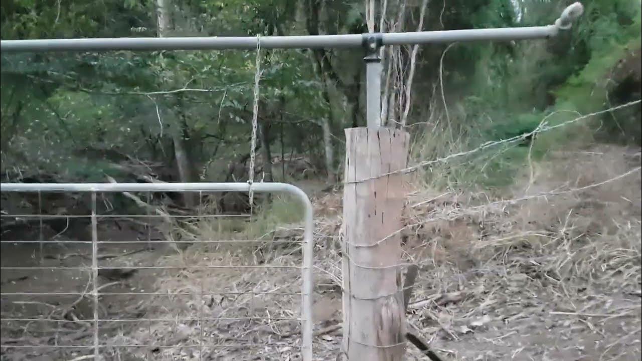 Flood gate through wash way building a fence across a creek or gully