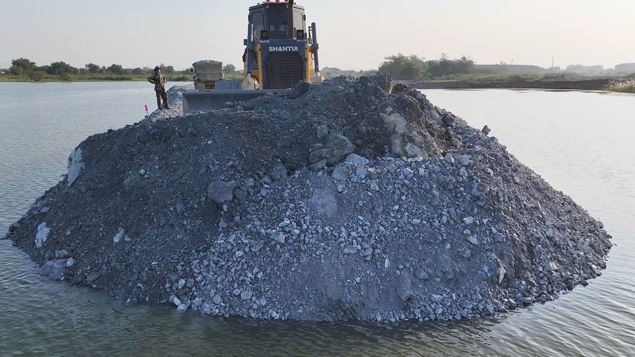 It's unbelievable! The project to pour large rocks across the lake had to be continued by bulldozers