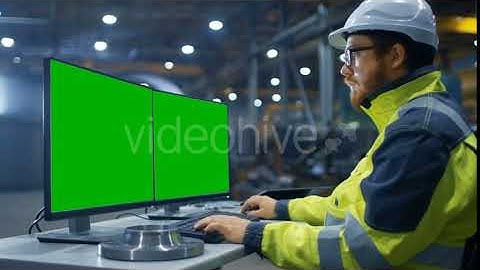 Industrial Engineer Works on the Personal Computer with Two  Green Mock-up Screens.