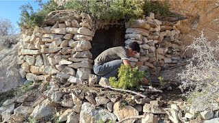 Construction of warm survival shelter: bushcraft stone hut with stone fireplace