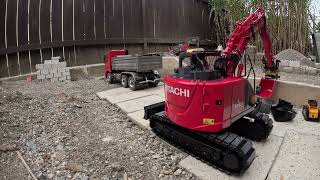 Teaser zum neuen Hitachi Zaxis 135 US in Rot, Löffel abladen.