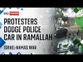 Israel-Hamas war: Protesters dodge police car driving around roundabout in Ramallah