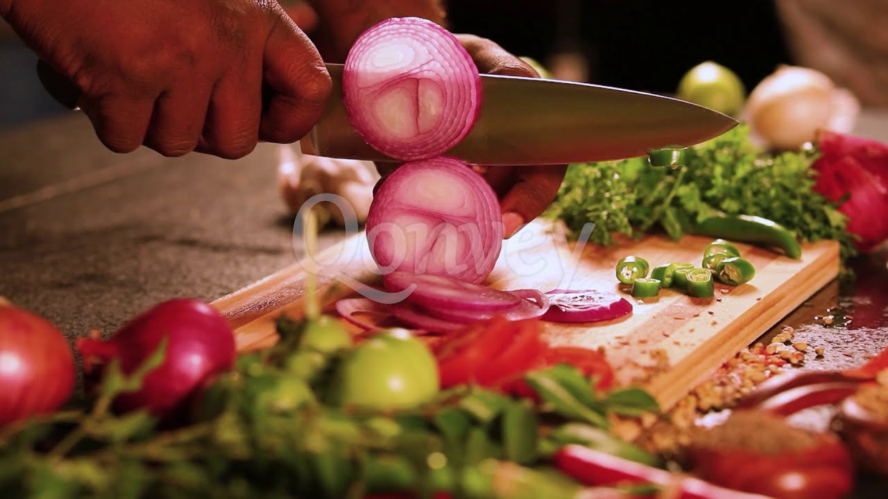 Chopping onion on board with knife and vegetables around | Stock Video | Qonvey