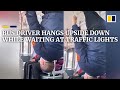 Bus driver in China hangs upside down while waiting at traffic lights