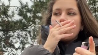 A girl smoking a cigarette in a park answers questions about addiction and crushes it.