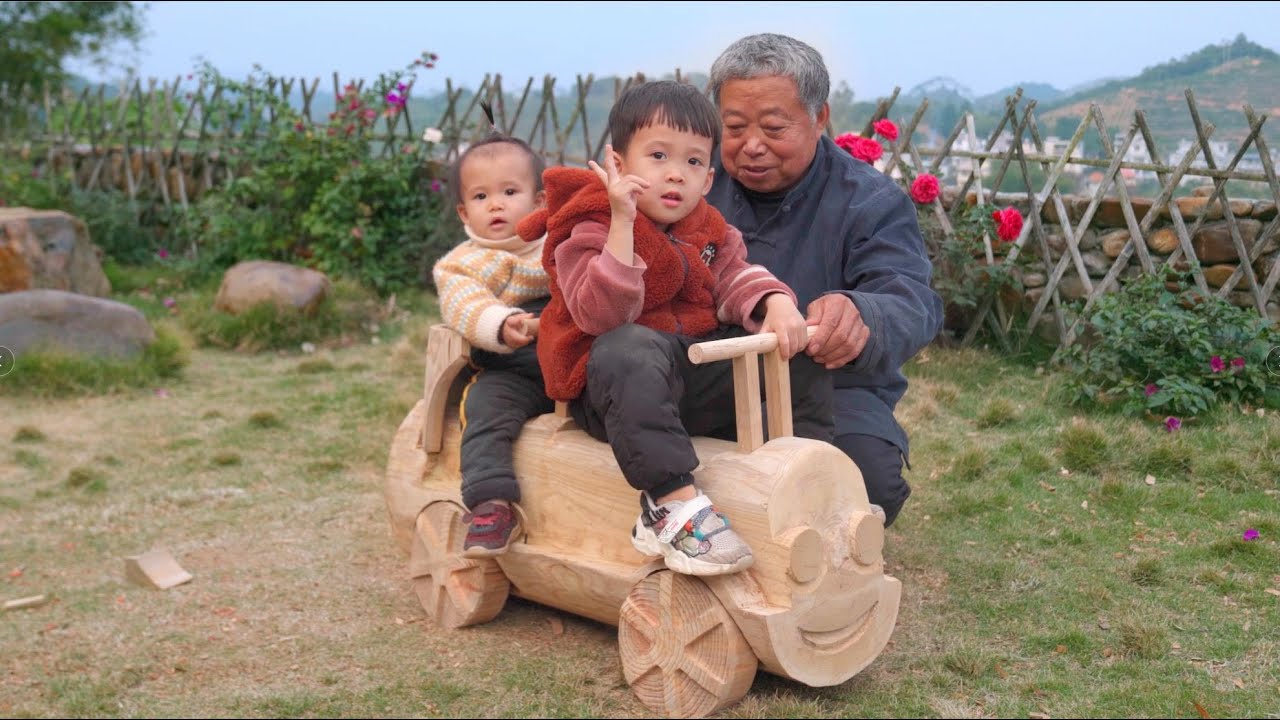 阿木爷爷扛回一根大木桩制作木头车，配上四个轮子，孙子孙女坐上好开心