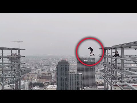 Man walks on slack line between 2 graffiti towers