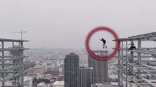 Man walks on slack line between 2 graffiti towers