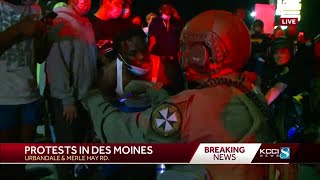 Protesters speak to officers while officers kneel on Merle Hay Road