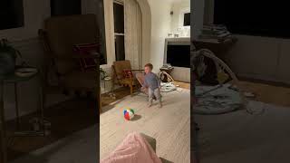 Boy attempts to kick beach ball but misses then foot hits top off ball and he falls in living room