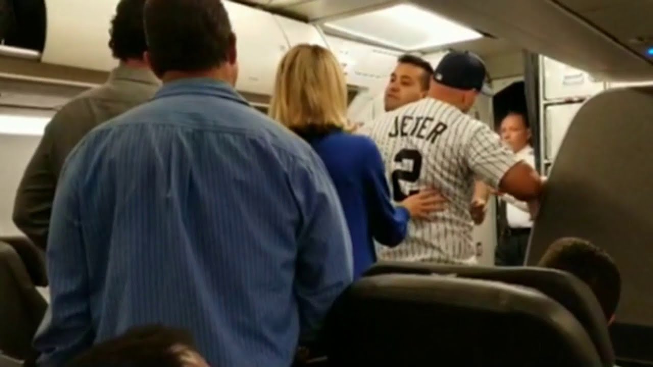 Видео из салона самолета показывает, как мужчину выводят из самолета после того, как он пробежал ...