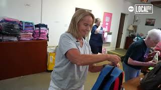 Volunteers pack book bags full of school supplies for families dealing with cancer