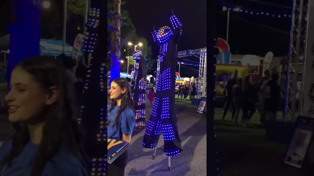 LED robot walkers perform on stilts
