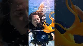 Female scuba diver demonstrating how to take and put back on scuba mask underwater