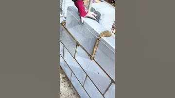 Worker applies cement mortar between concrete blocks to build a strong and even wall foundation