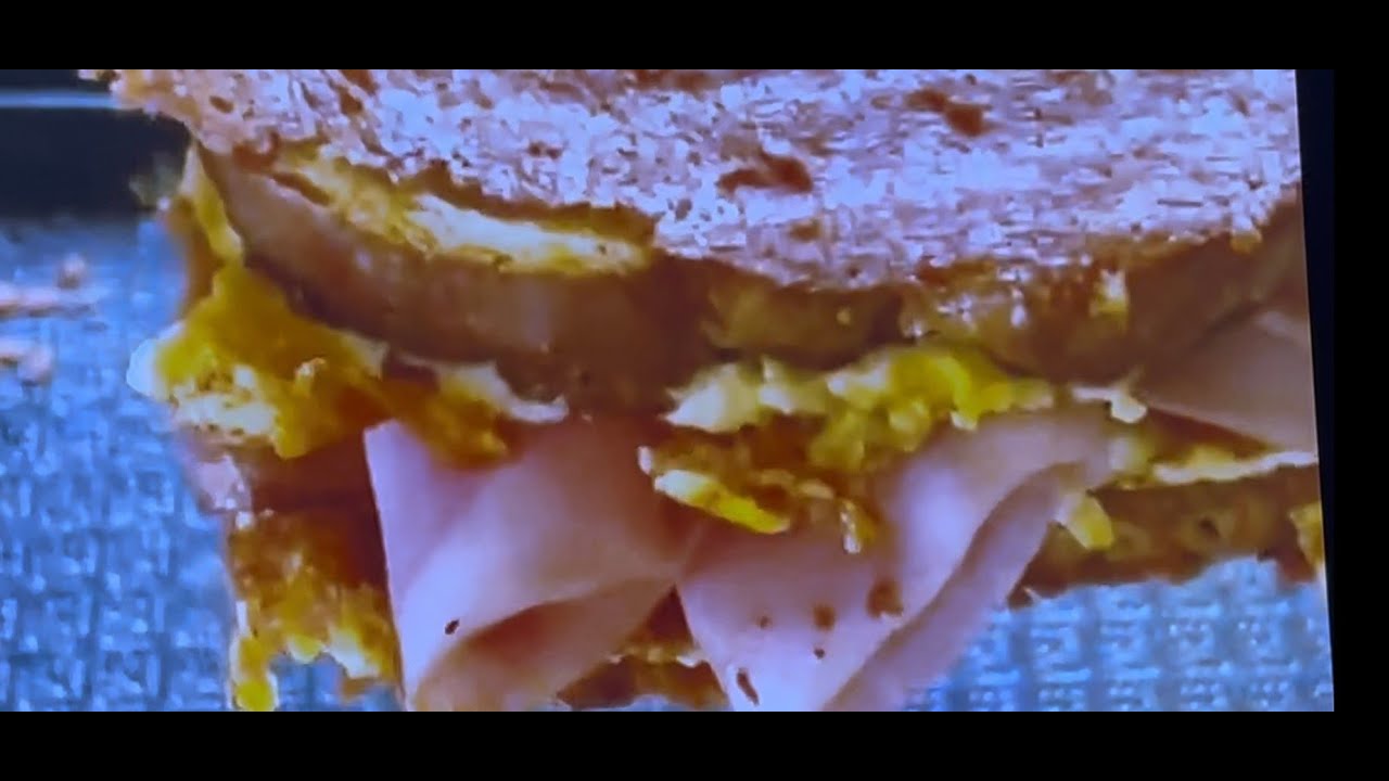 Хрустящий сэндвич с беконом и ветчиной, приготовленный на плоской жарочной поверхности.