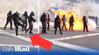 Daring Greek cop kicks Molotov cocktail as firebombs explode inches away during protest in Athens
