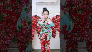 The top is a light blue jacket adorned with vivid red, green, and yellow floral designs, and the