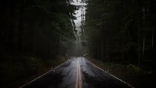Rain and thunder on the road in a gloomy mountain forest