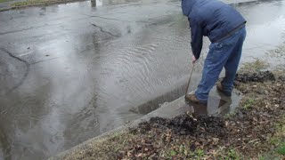 Unblocking a Clogged Street Drain for Safe Traffic Flow