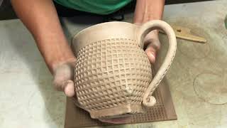 Hand building a bellied, square foot mug