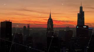 Orange hues from the sunset illuminate Manhattan skyline, with Empire State Building and Metlife