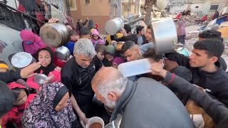 Starving Palestinians in Gaza refugee camp receive hot meals from volunteers at start of Ramadan