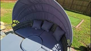 Round outdoor daybed with an adjustable sun canopy that is a 4 piece sectional with pillows