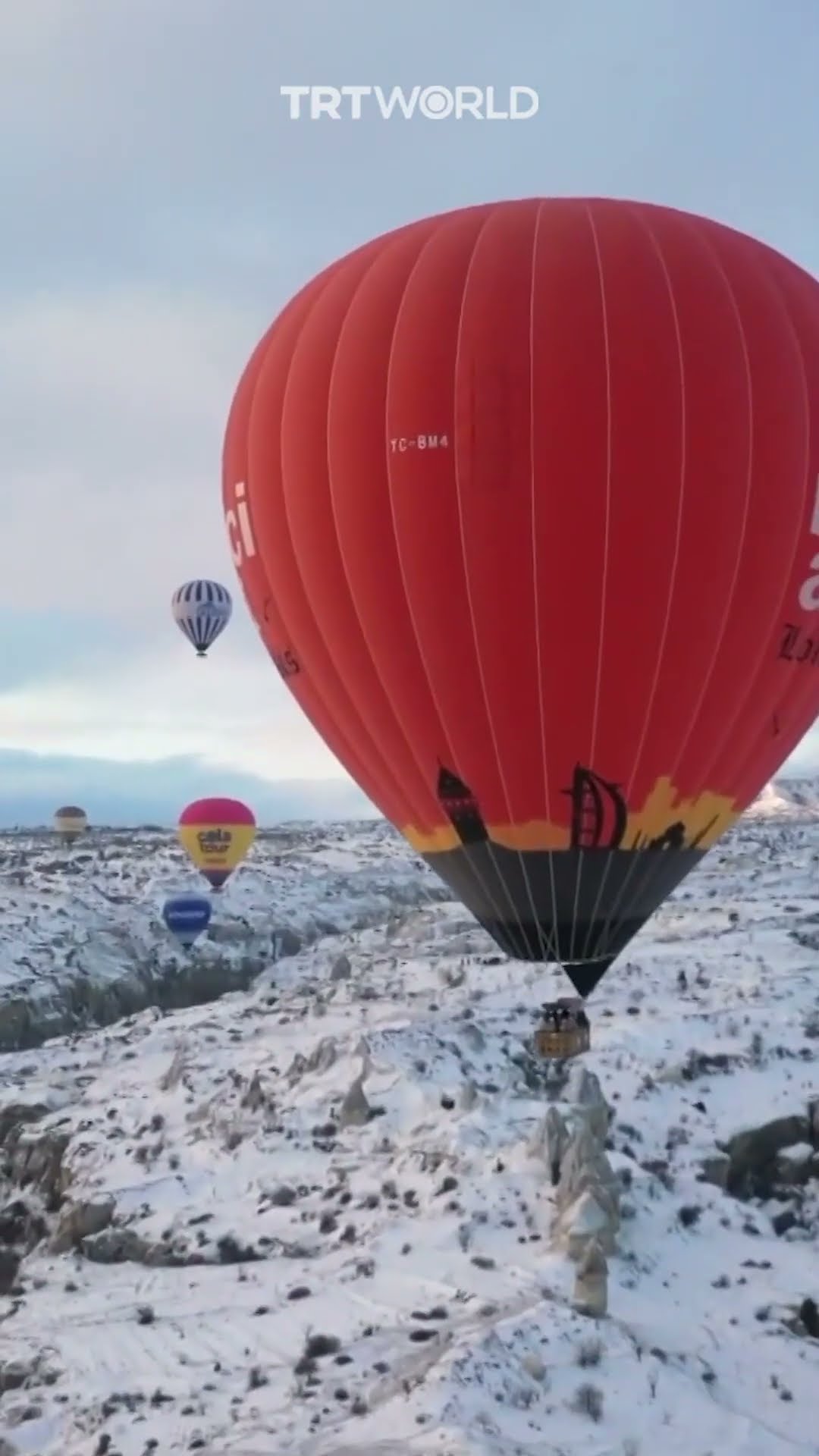 Hot air balloons soar over Cappadocia's snow-capped chimneys