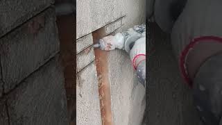 drilling a vertical slot into a stone wall using a power tool to install wiring pipes