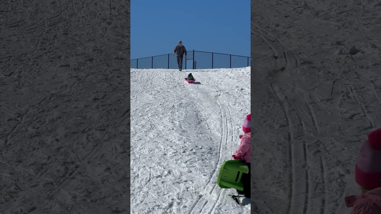 Boy rides sled down hill and crashes into little girl in pink jacket
