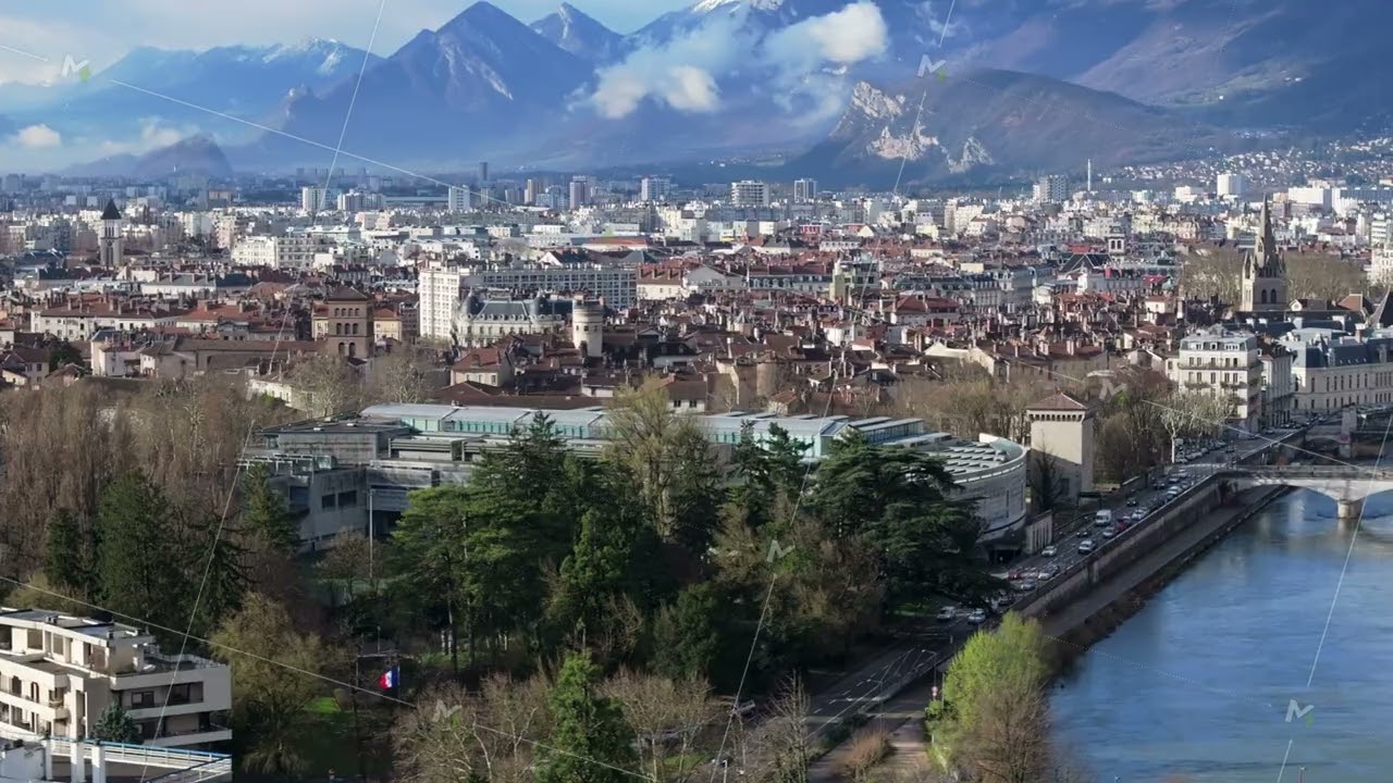 Panoramic cityscape of Grenoble, nestling beside Isere river with snow dusted French Alps towering