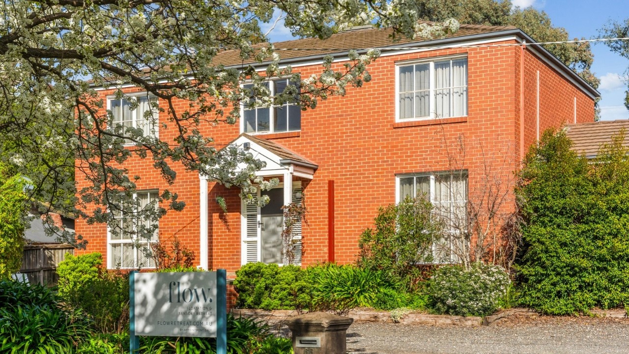 Two storey red brick home behind a flowering tree with established gardens at 66 Spring Gully Road, Spring Gully