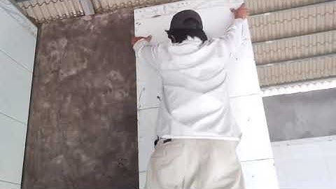 có hai người thợ vẫn tiếp tục ốp gạch ngôi nhà nóc thái cho kịp tiến độ