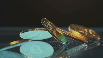 VideoVault Stock Video: 5 bitcoin coins falling onto a table in slow motion