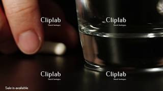 Man's fingers take white oval pill and transparent glass of water rises and then lowers - Front View