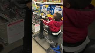 Toddler Trying to Drive Shopping Cart as It Pushes Dad along the Way