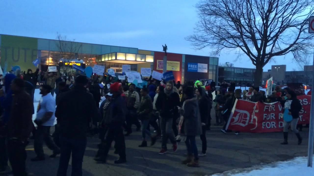 Protesters march down Kearsley Street in Flint before debate
