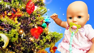 Baby Annabell doll celebrates New Year. The baby doll decorates New Year tree with toys.