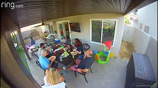 Family sits down to eats in backyard then boy runs through and breaks screen door (Security camera)