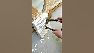 Man using hand tools (hammer/wrench) to modify a stack of white wavy construction paneling
