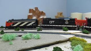 MTH O scale Grand Trunk Western F3, GP9 diesel locomotives pull a train of trailers on flat cars