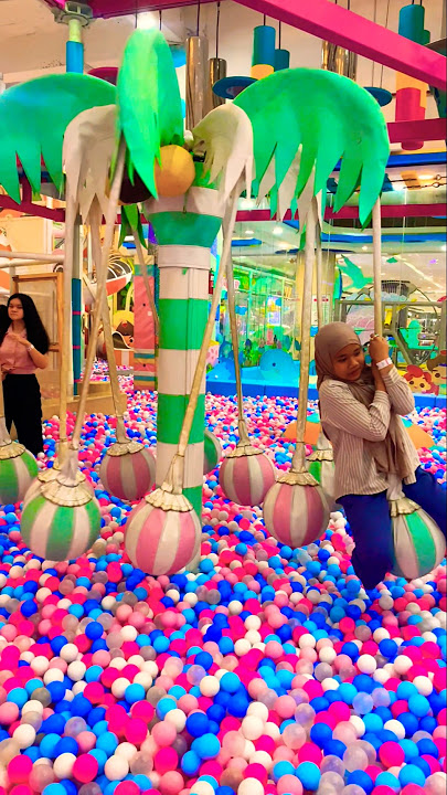 Kakak pegangan balon hijau di kolam bola warna-warni