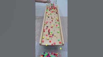 Colored Beads Rolling on a Wooden Board with Obstacles Oddly Satisfying