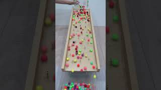 Colored Beads Rolling on a Wooden Board with Obstacles Oddly Satisfying